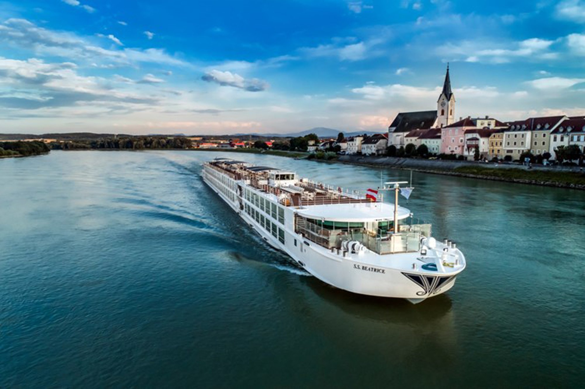 2167_50034_resize_0_500 River cruise ship sailing past a charming European riverside town with church spire and colorful architecture on the Danube
