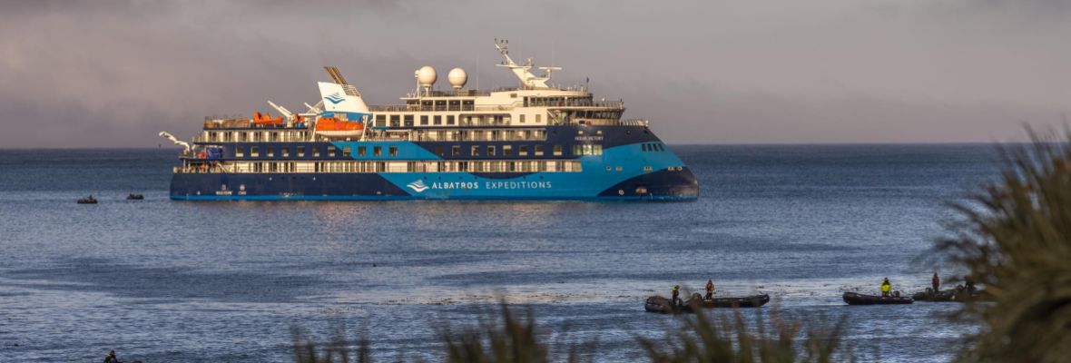 Albatros Expeditions Ship in Coastal Waters The Polar Latitudes expedition cruise ship anchored in calm coastal waters with small Zodiac boats nearby.
