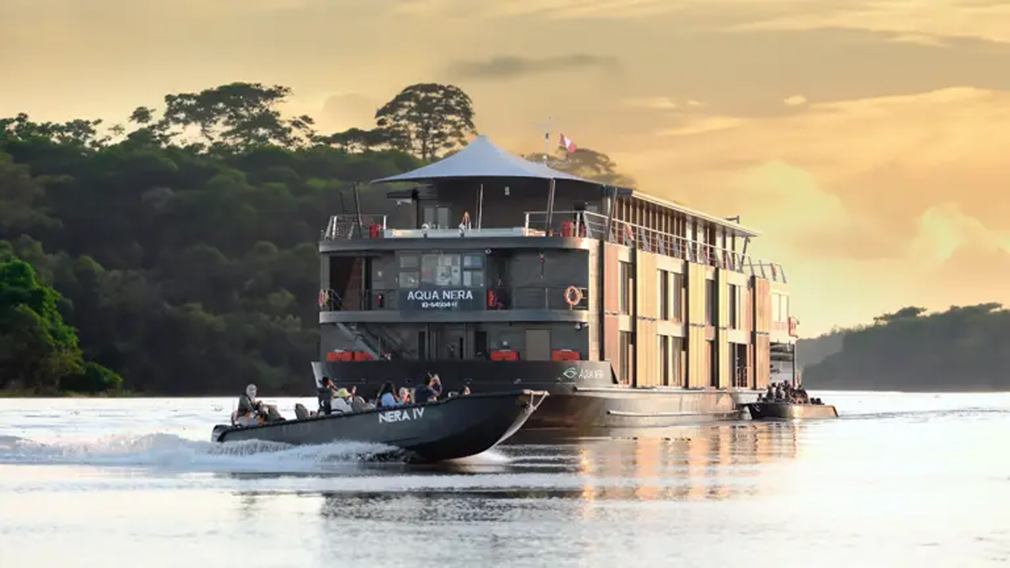 Amazon River Cruise Vessel at Sunset A luxury river cruise ship named Aqua Nera navigating through a lush Amazon rainforest landscape