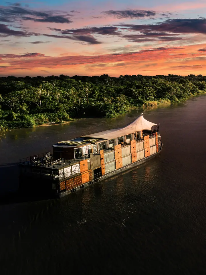 Amazon River Cruise at Sunset A traditional wooden riverboat cruise vessel navigates the Amazon River during a stunning golden