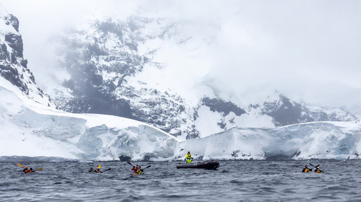 Antarctic Expedition Zodiac Adventure Adventure travelers in inflatable Zodiac boats explore the pristine Antarctic landscape, navigating