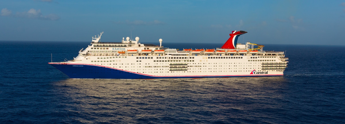 Carnival Cruise Ship at Sea A large white Carnival cruise ship sailing on blue ocean waters with a clear sky background. The vessel displays the distinctive red Carnival funnel and appears to be mid-voyage.