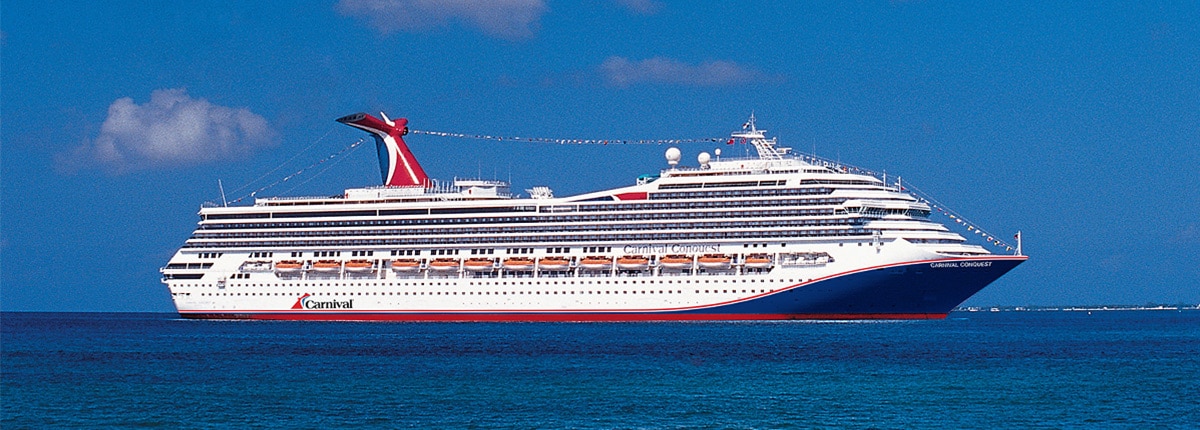 Carnival Cruise Ship at Sea A large Carnival cruise ship sailing on deep blue waters under a clear sky with scattered clouds
