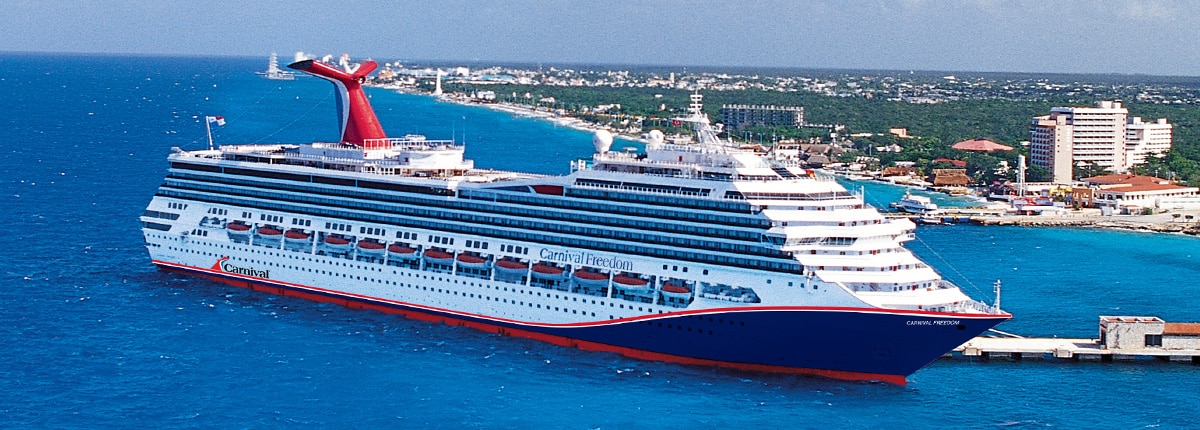 Carnival Freedom Cruise Ship in Port A large Carnival cruise ship docked at a coastal destination, featuring a distinctive red, white