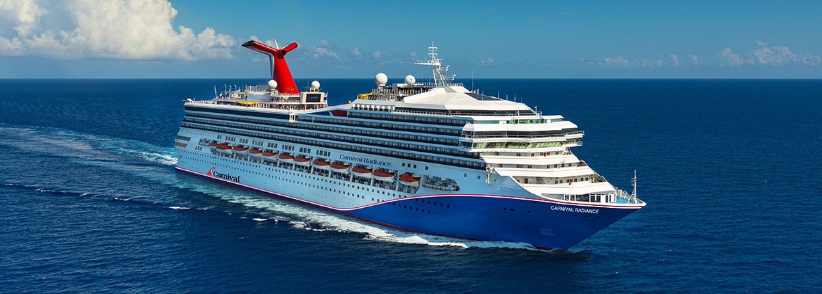 Carnival Radiance Cruise Ship at Sea A large blue and white Carnival cruise ship sailing on open blue waters under a cloudy sky