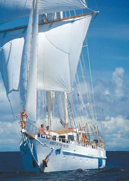 Classic Sailing Ship Under Full Canvas A stunning tall ship with white sails fully deployed against a brilliant blue sky with scattered clouds, featuring multiple crew members visible on deck.