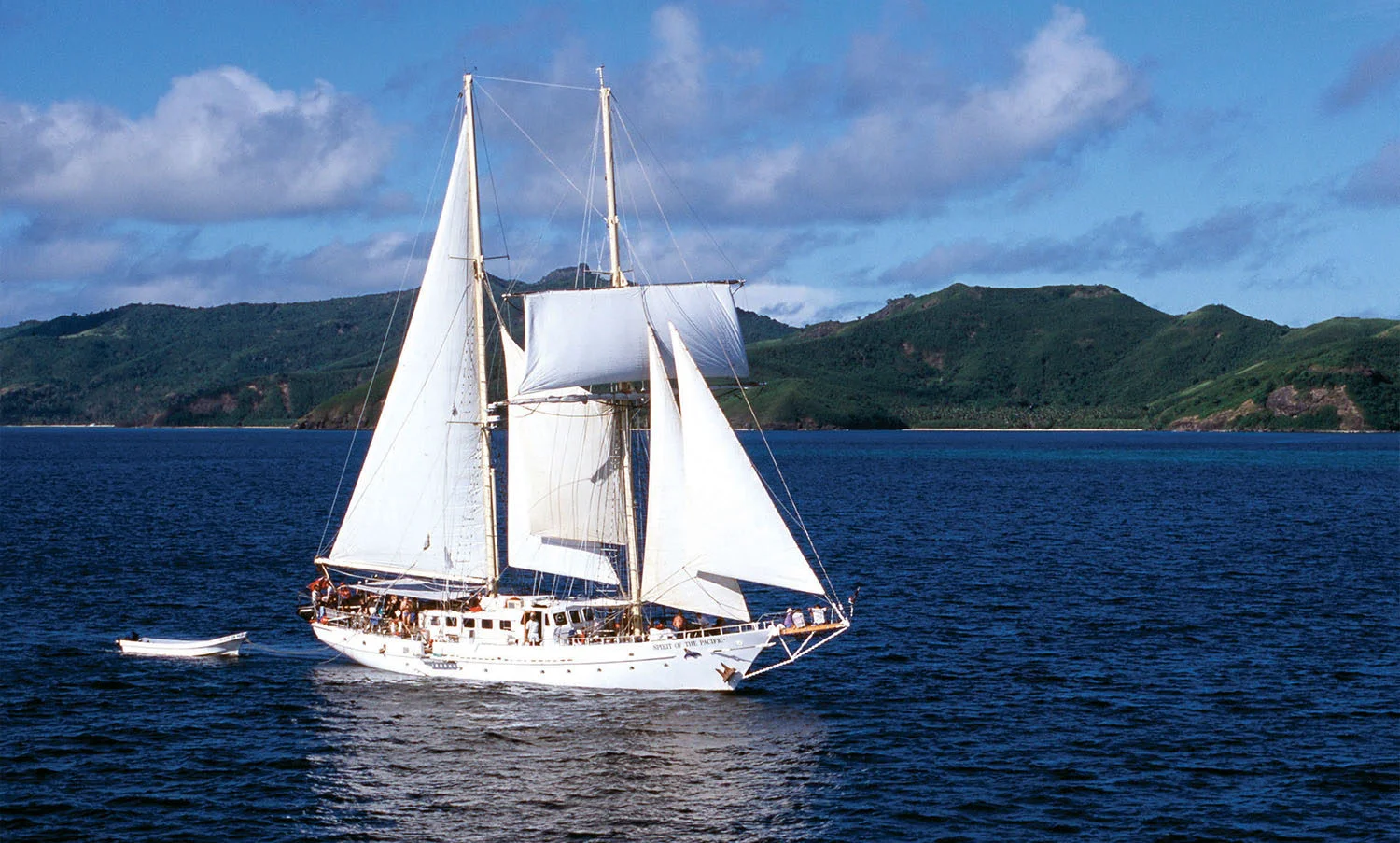 Classic Sailing Vessel in Tropical Waters A stunning white two-masted sailing ship anchors in crystal-clear tropical waters, with lush