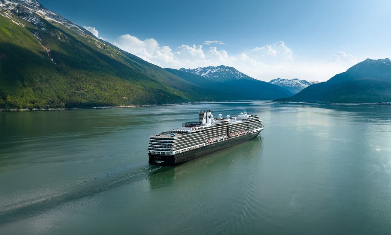 Cruise Ship in Alaskan Mountain Fjord Holland America cruise ship sailing through a scenic Alaskan mountain fjord with dramatic peaks and calm waters.