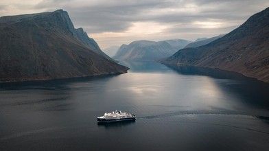Cruise Ship in Norwegian Fjord A passenger cruise ship navigates through a dramatic Norwegian fjord surrounded by steep mountain