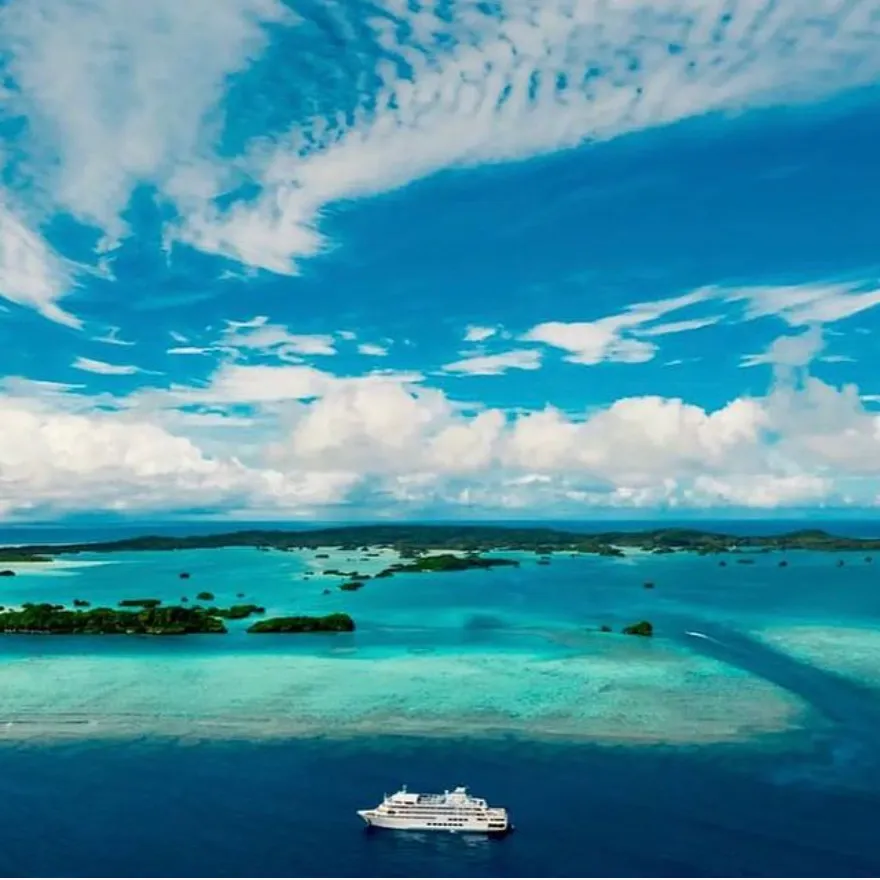 Cruise Ship in Tropical Island Waters An aerial view of a modern cruise ship anchored in crystal-clear turquoise waters surrounded
