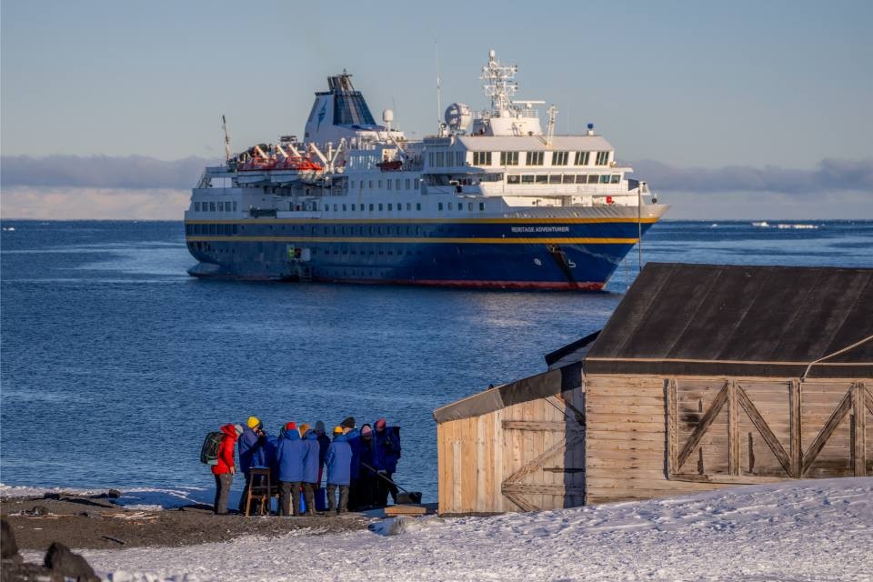 Expedition Ship Arctic Exploration Landing A group of expedition passengers in winter clothing gather on an Arctic beach near a wooden