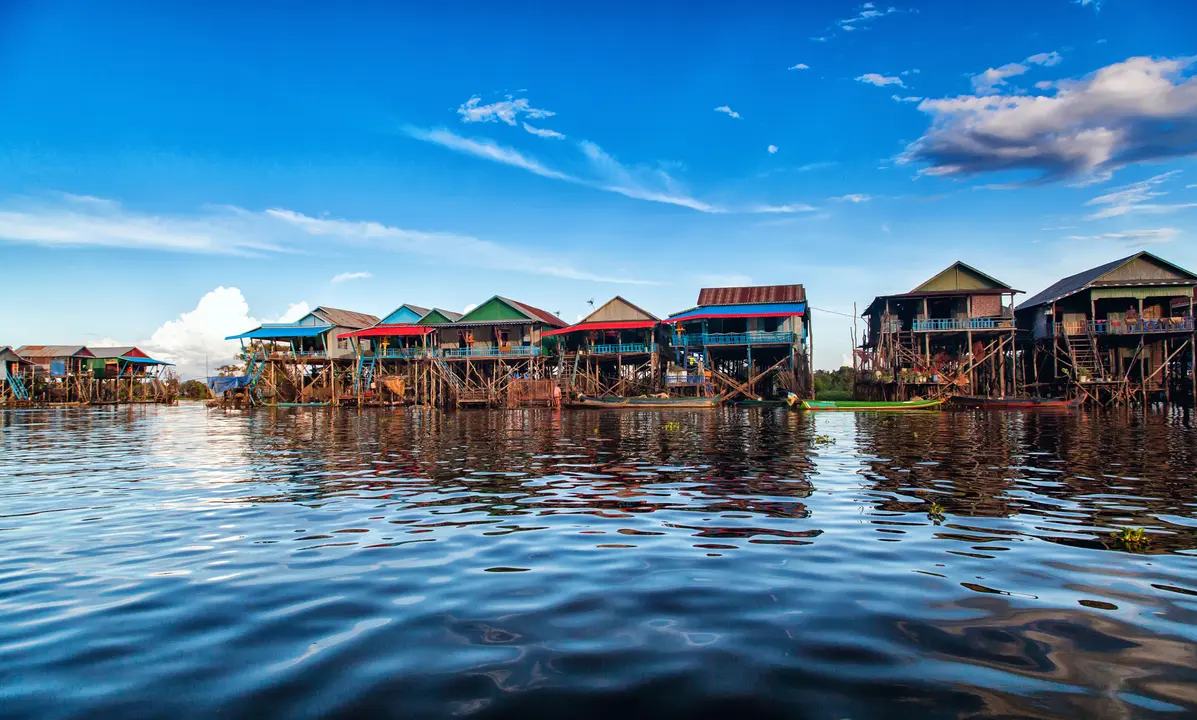 Floating Village on Tonlé Sap Lake A vibrant floating village featuring traditional wooden stilt houses with colorful roofs reflected