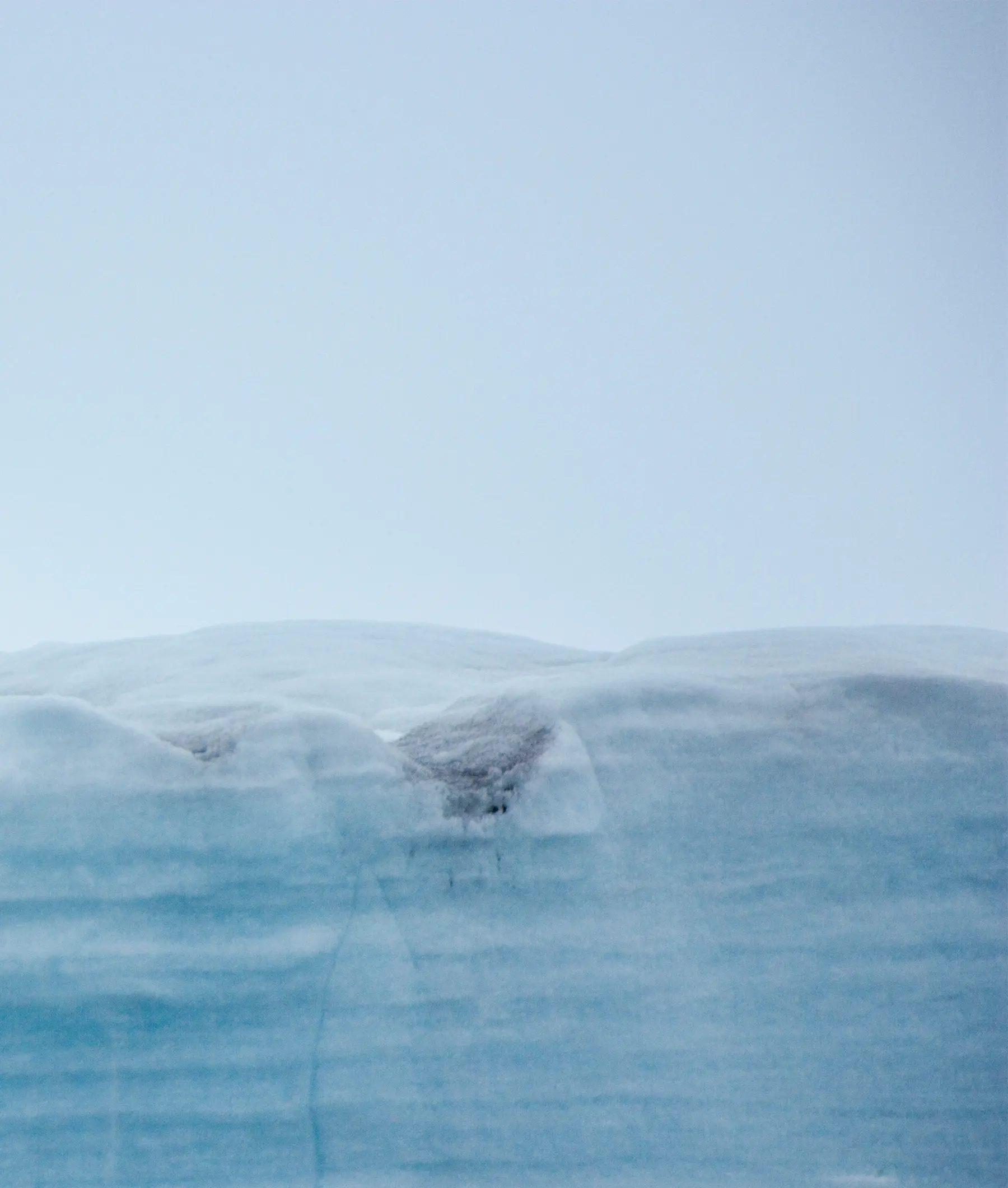 Glacial Ice Formation in Arctic Waters A striking photograph of a massive blue glacier or iceberg with layered ice formations rising above