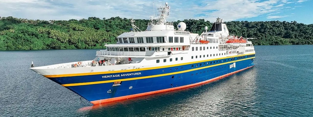 Heritage Adventurer Expedition Cruise Ship The Heritage Adventurer, a modern expedition cruise vessel, anchors in turquoise tropical waters