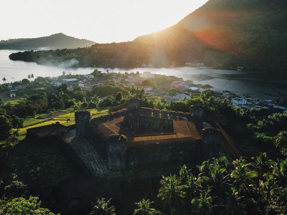 Historic Fort Overlooking Tropical Island Village An aerial view of a weathered colonial-era fortification overlooking a lush tropical island
