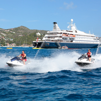 Jet Skis Racing Near Cruise Ship Two jet skis speed across bright blue ocean waters with a white cruise ship in the background, set