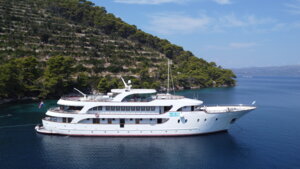Luxury Cruise Ship Anchored in Mediterranean Waters A multi-deck luxury cruise vessel is anchored in pristine turquoise Mediterranean waters adjacent