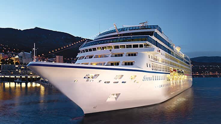 Luxury Cruise Ship at Night A pristine white cruise ship docked at a scenic harbor with mountains in the background during twilight hours.