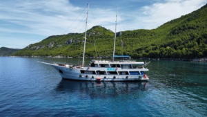 Luxury Gulet Cruise in Mediterranean Waters A striking two-masted luxury gulet sailing vessel anchors in crystal-clear turquoise waters