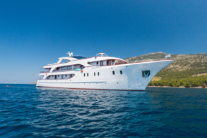 Luxury Motor Yacht Anchored in Mediterranean Waters A pristine white motor yacht with multiple decks anchored in crystal-clear turquoise waters near