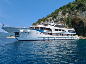 Luxury Motor Yacht Anchored in Mediterranean Waters A sleek, modern motor yacht with multiple decks and white hull anchors in crystal-clear turquoise