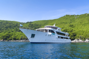Luxury Motor Yacht Anchored in Tropical Waters A sophisticated white multi-deck motor yacht is anchored in crystal-clear turquoise waters adjacent