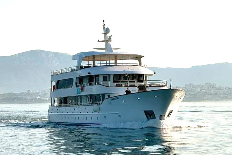 Luxury Motor Yacht in Coastal Waters A sophisticated multi-deck motor yacht with light blue and white hull cruising through calm coastal