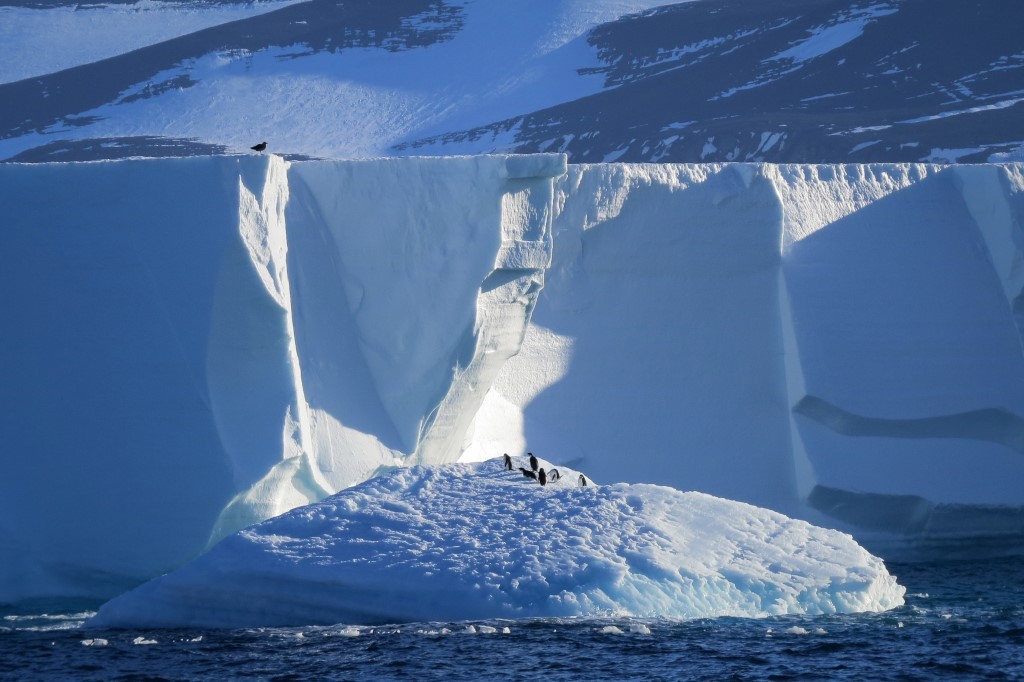 Majestic Iceberg in Antarctic Waters A stunning massive iceberg with towering white walls and deep blue crevasses rises dramatically