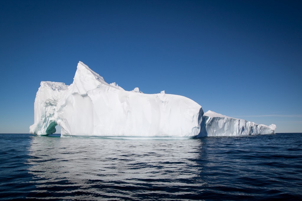 Massive Iceberg Floating in Arctic Waters A large, sculptural iceberg with brilliant white peaks and turquoise-tinted crevices floats in deep