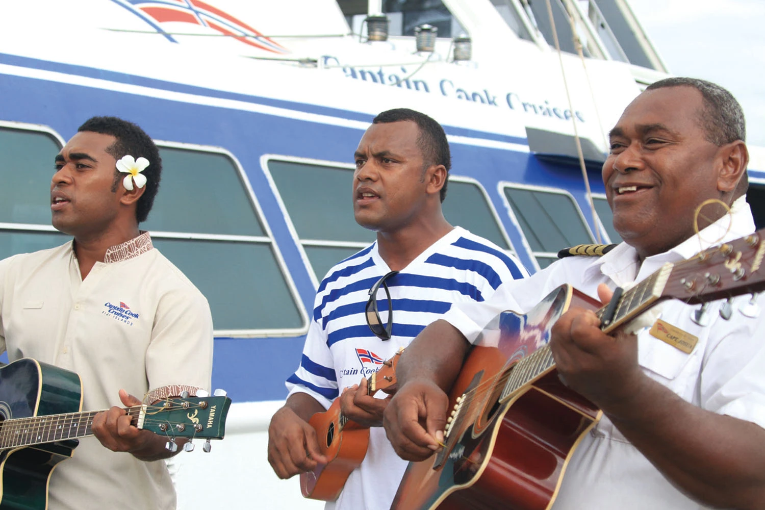 Musical Performance on Cruise Ship Deck Three musicians perform together with acoustic guitars on the deck of a Dawain Bank Cruises vessel