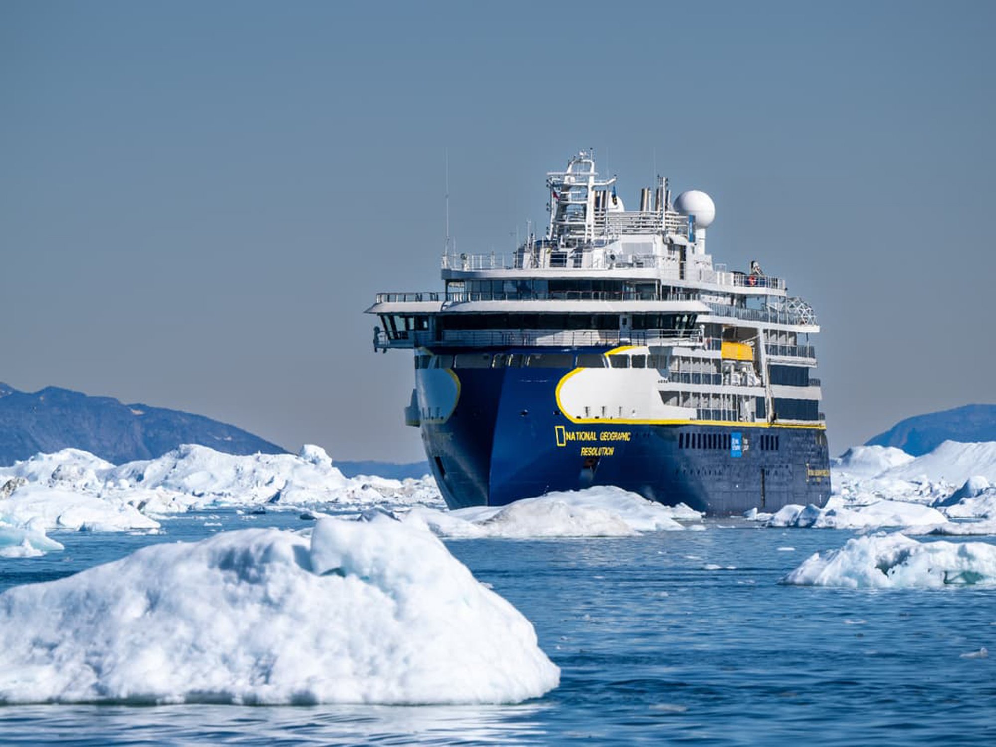 National Geographic Resolution in Antarctic Ice The National Geographic Resolution cruise ship navigates through icebergs and pack ice in Antarctica, surrounded by snow-covered mountains and pristine glacial landscape.