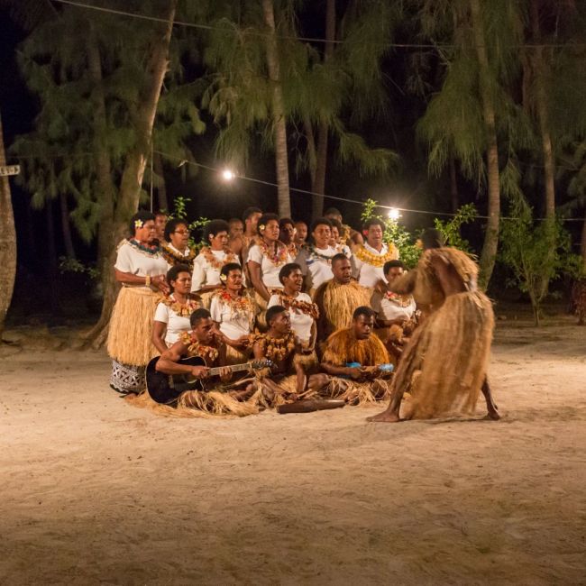 Pacific Island Cultural Evening Performance A vibrant nighttime cultural gathering on a sandy beach featuring a large group of performers