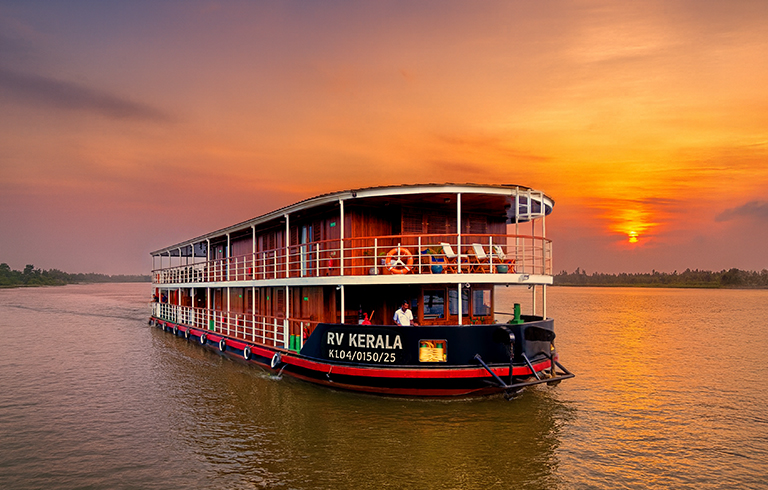 RV Kerala River Cruise at Sunset A multi-deck river cruise boat named RV Kerala sailing on a tranquil river during a vibrant orange