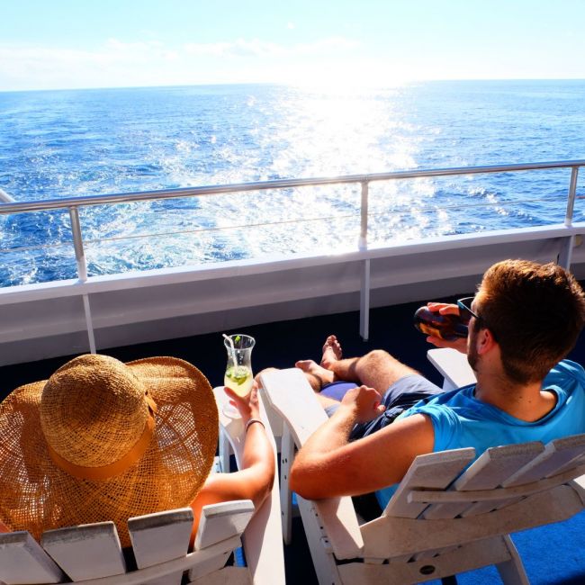 Relaxing on Cruise Ship Deck at Sea A passenger enjoys a leisurely afternoon on a cruise ship's deck, relaxing in a lounge chair with