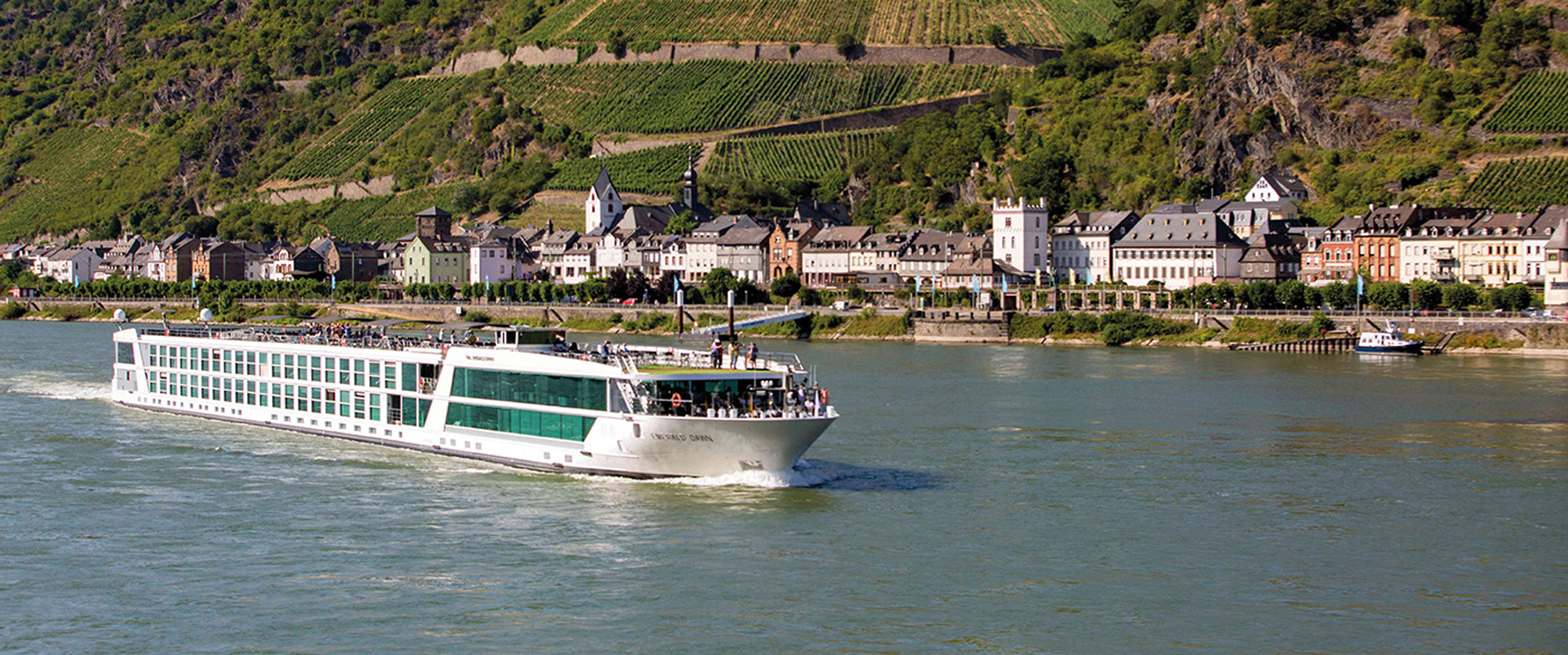 A river cruise ship sailing along a scenic European river valley with vineyard-covered hillsides.