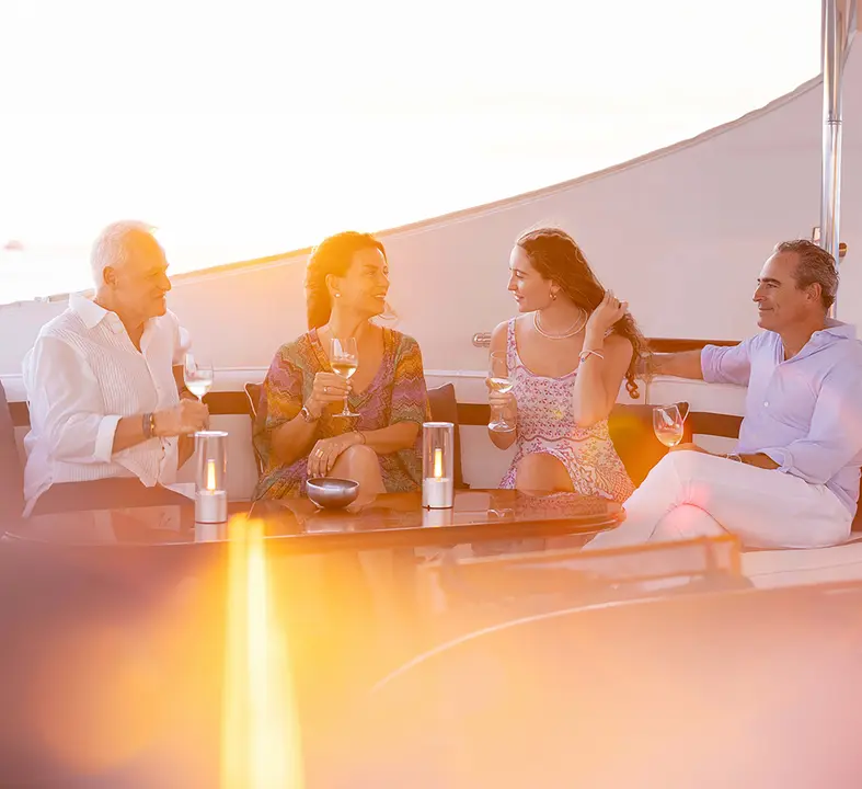 Sunset Cocktail Hour on Cruise Ship Deck Four well-dressed guests enjoy cocktails and conversation on an upper deck of a cruise ship during