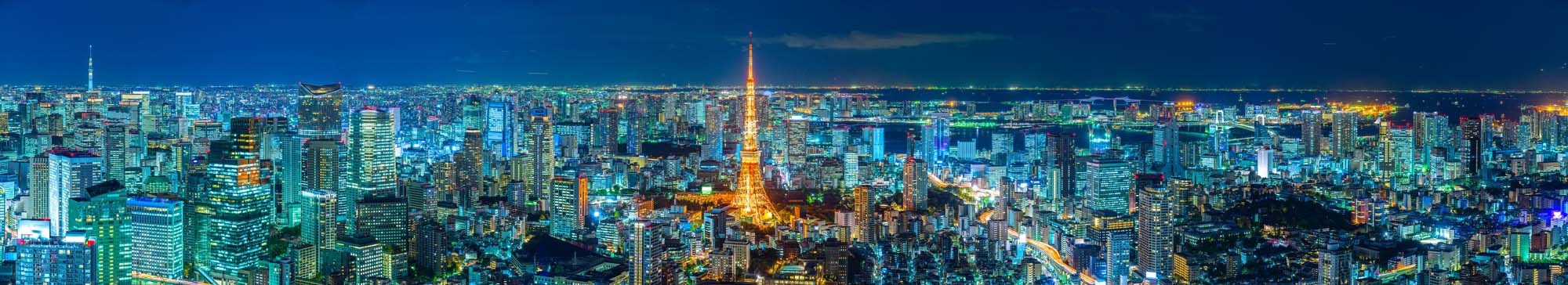 Tokyo Skyline at Night A stunning panoramic view of Tokyo's cityscape at night, featuring the iconic Tokyo Tower illuminated in orange amid dense, glowing skyscrapers and urban landscape.
