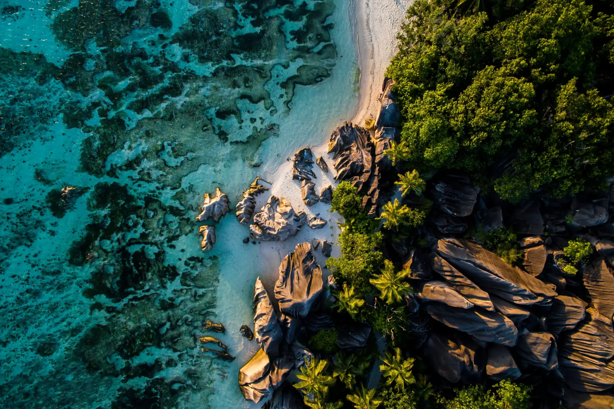 Tropical Beach Cove with Granite Boulders An aerial view of a pristine tropical beach featuring turquoise crystal-clear waters, white sand