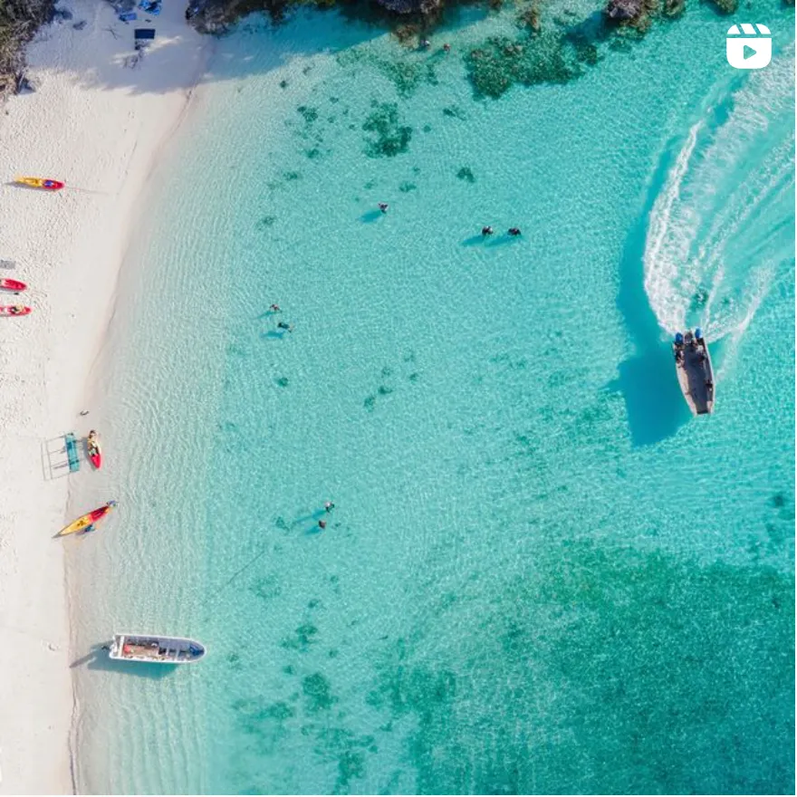 Tropical Beach Paradise with Speedboats An aerial view of a pristine tropical beach with crystal-clear turquoise waters, white sand