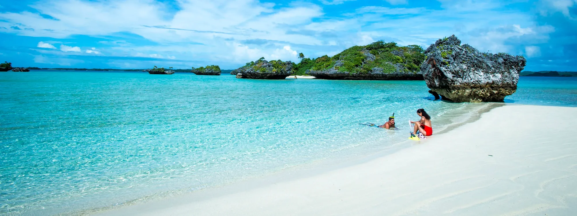 Tropical Island Beach Paradise with Crystal Waters A pristine white sand beach with turquoise crystal-clear waters featuring a family enjoying