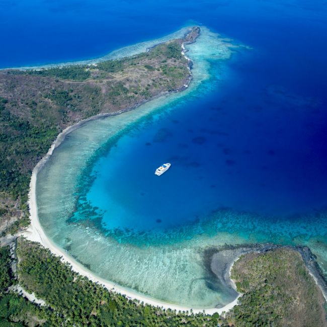 Tropical Island Paradise Aerial View An aerial view of a pristine tropical island featuring a crescent-shaped white sand beach