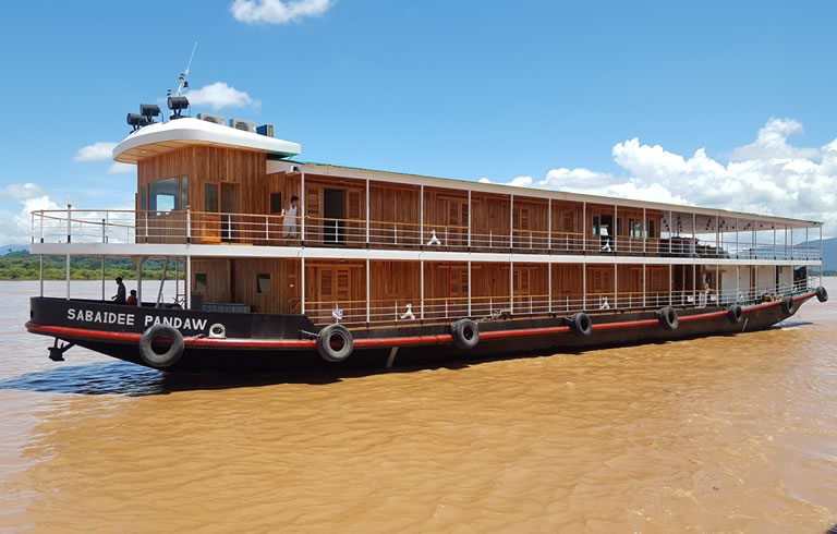 Wooden River Cruise Boat on Muddy Water A two-deck wooden river cruise boat named 'Sabaidee Pandaw' sailing on a muddy brown river with