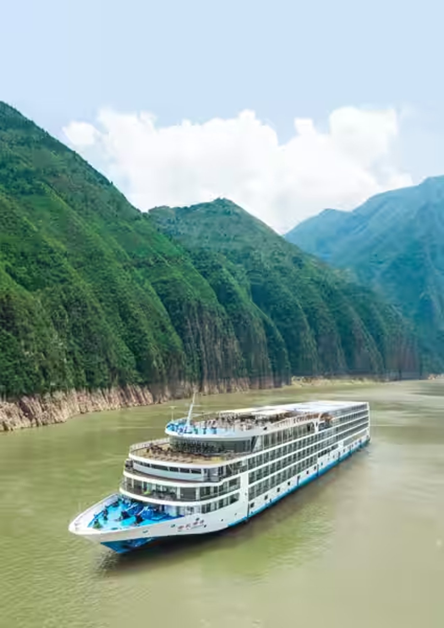 t-ship-Century-Paragon-China-exterior-5-supplied-edit A modern river cruise ship navigates through a scenic gorge with dramatic green-forested mountains rising steeply on both sides and misty peaks in the distance.