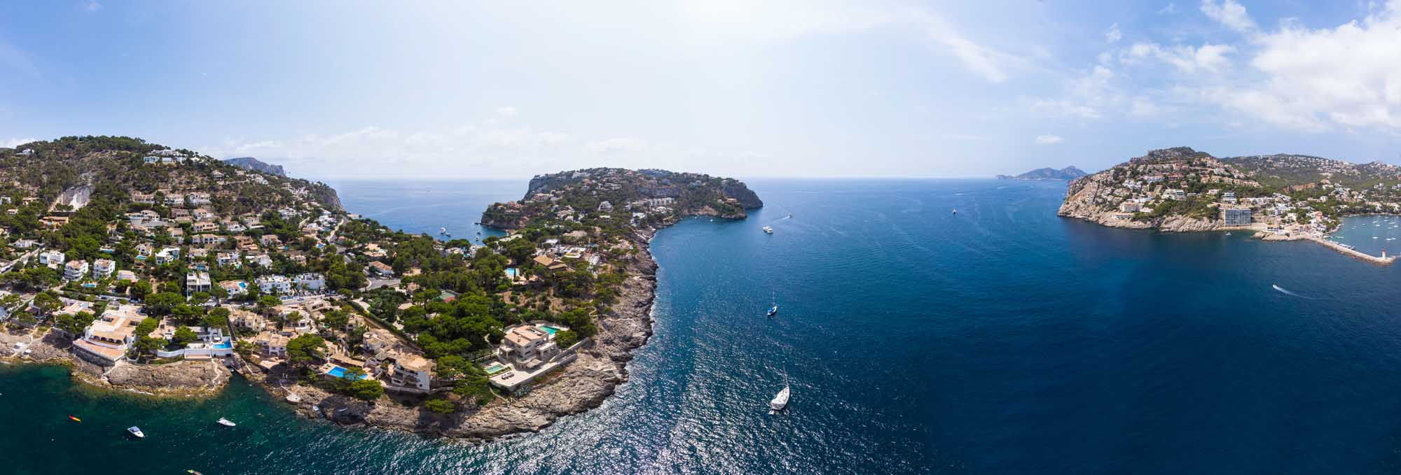 Aerial View of Port d’Andratx, Mallorca A stunning aerial photograph of Port d'Andratx in Mallorca, Balearic Islands, showcasing dramatic rocky coves, crystal-clear turquoise waters, luxury Mediterranean villas nestled on hillsides, and numerous moored yachts.