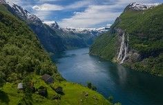 Alpine Fjord with Waterfall and Mountain Peak A stunning alpine fjord landscape featuring a pristine turquoise-blue lake surrounded by steep