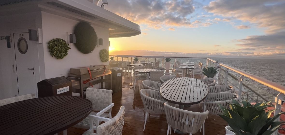 Cruise Ship Lido Deck at Sunset An expansive outdoor lido deck aboard a cruise ship featuring multiple dining tables with white