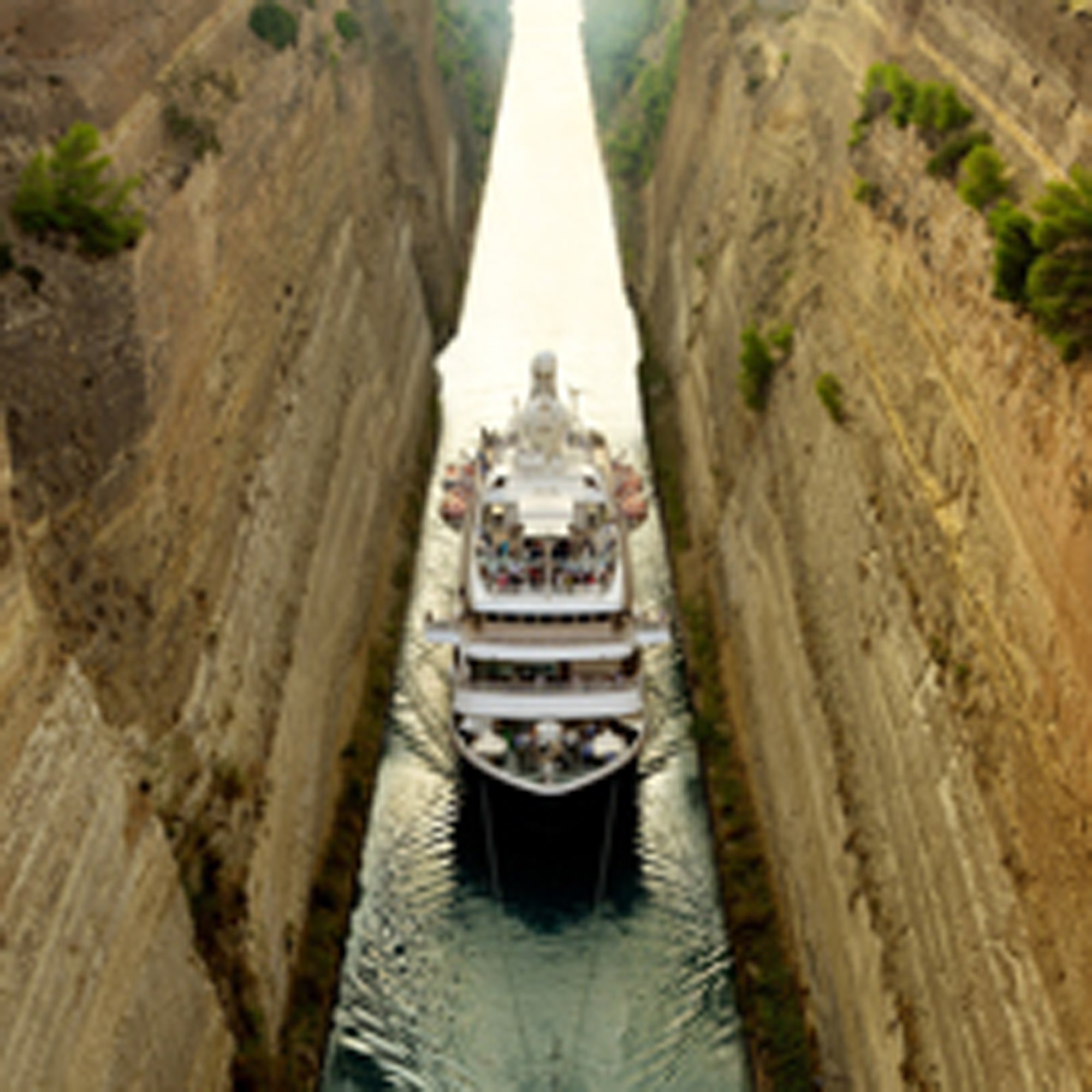 A cruise ship navigating through a narrow waterway with scenic coastline visible on both sides.