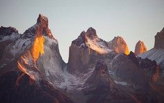 Dramatic Mountain Peaks at Golden Hour Towering granite peaks bathed in warm golden and orange light during sunset or sunrise, with snow