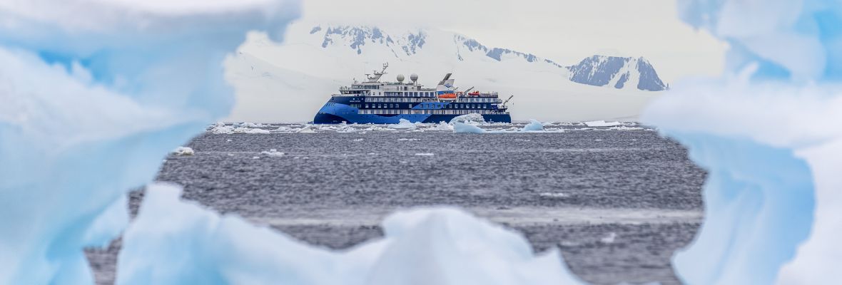 Expedition Cruise Ship in Antarctic Waters A modern expedition cruise ship navigates through icy Antarctic waters, framed by massive icebergs