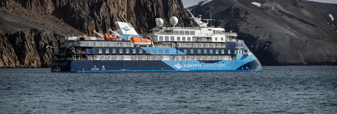 Expedition Ship at Deception Island, Antarctica An expedition cruise ship with distinctive blue and white livery is anchored in the waters off